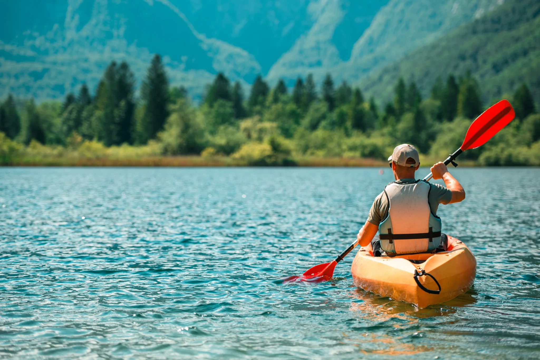 Persona che fa kayak su un lago circondato da montagne.