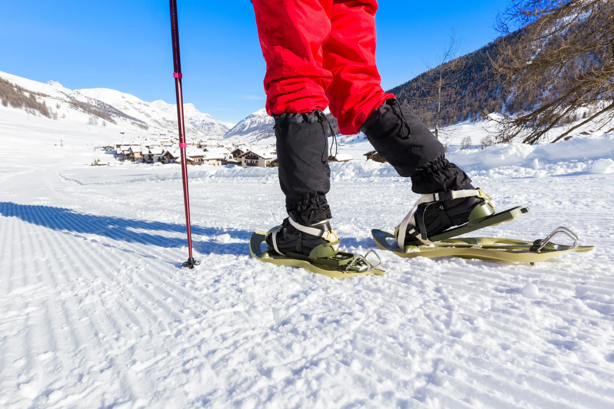 Escursionista con racchette da neve su sentiero innevato di montagna.