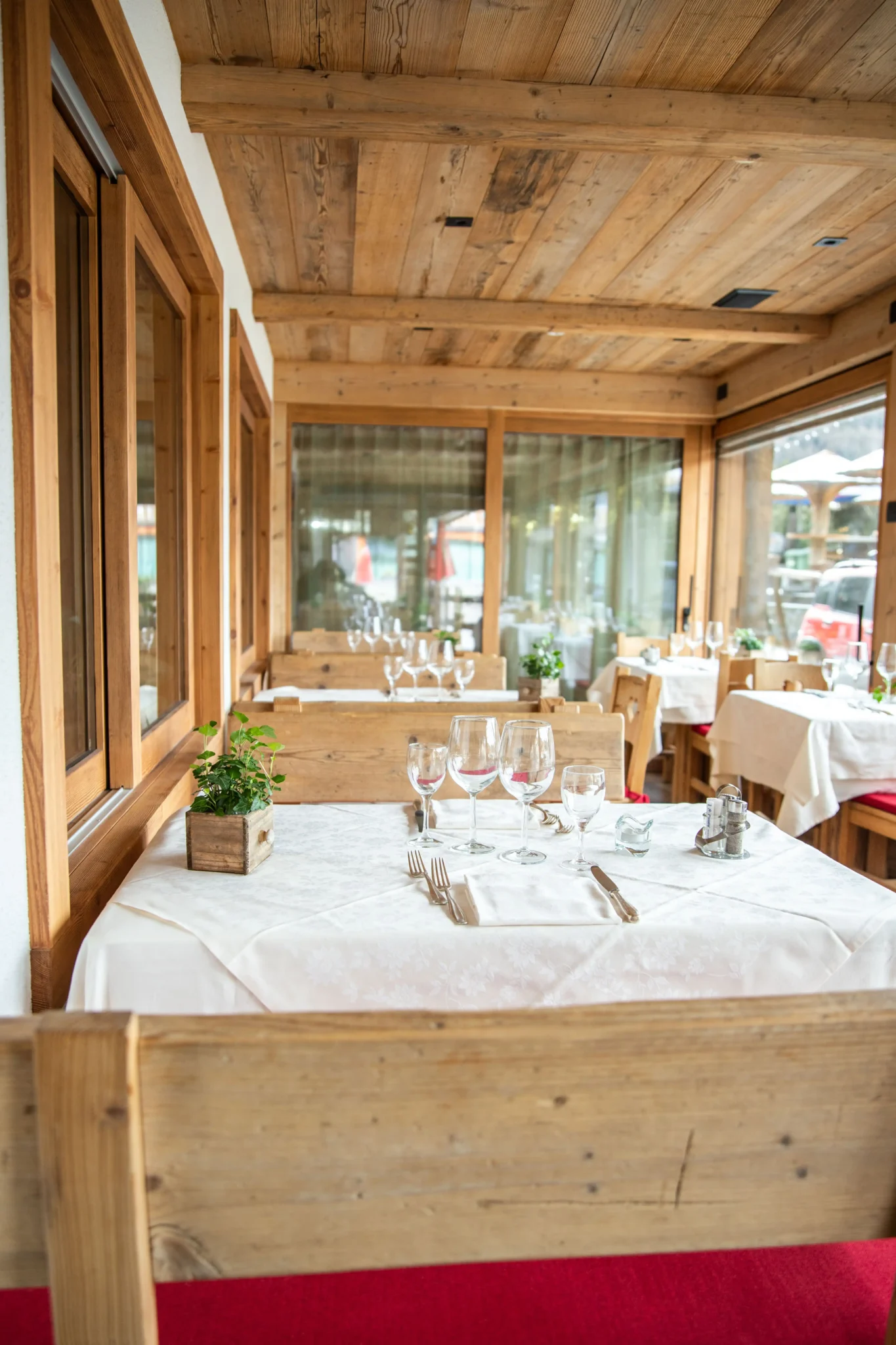 Interno di un ristorante rustico con tavoli apparecchiati, arredi in legno e luce naturale.