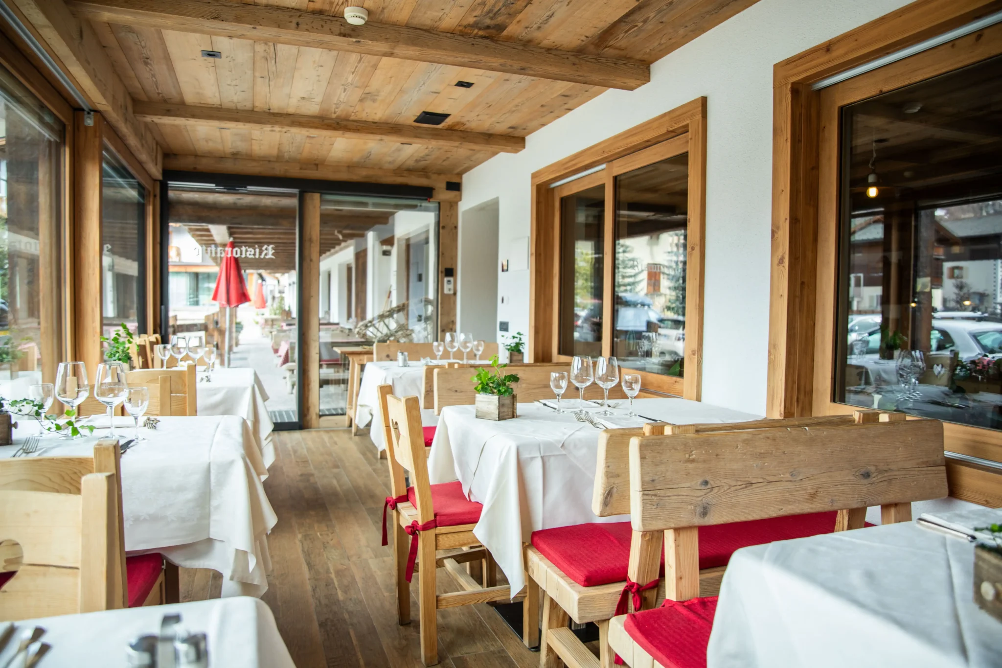 Interno di un ristorante rustico con tavoli apparecchiati e sedie in legno.